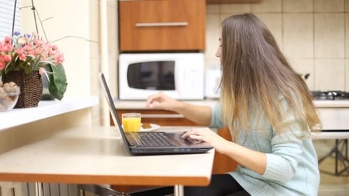 Young Woman Works on Laptop, Eats Snack