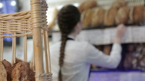 Woman Arranging Breads on Shelves at Bakery