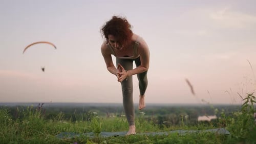 A Young Woman Keeps Her Balance By Doing Yoga Exercises on a Carpet in Nature in the Background a