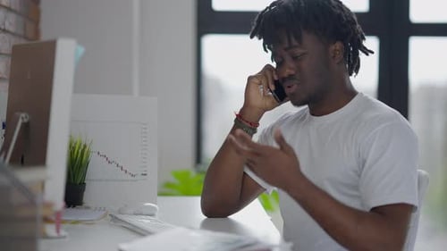 Young Adult Talking on Phone While Reviewing Graphs