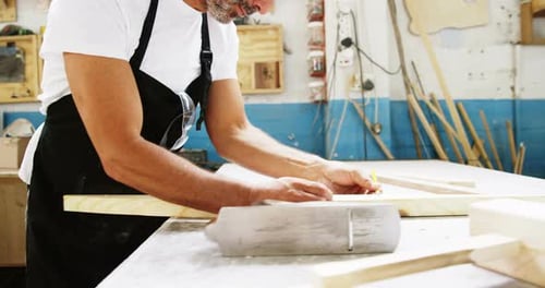 Man Crafts Wood at Workbench in Workshop