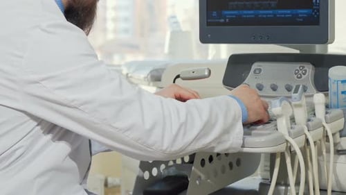 Cropped Rear View Shot of a Male Doctor Using Ultrasound Scanner