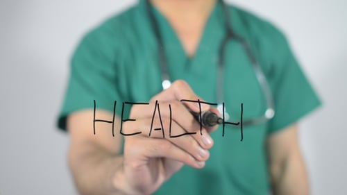 Doctor Writing Health with a Marker in Scrubs