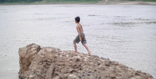 Junge spaziert auf einem Felsen in einem Fluss