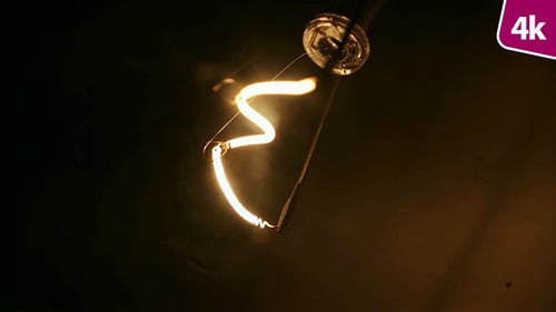 Bright Lightbulb Filament Against Dark Background