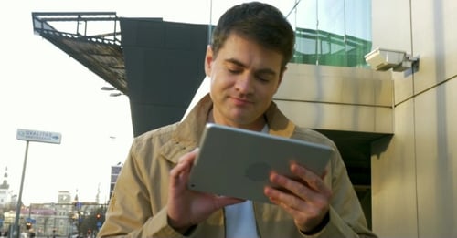 Man Using Tablet Computer On The Go In City