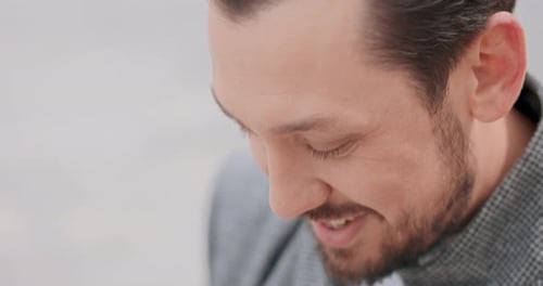 Close Up of Young Man's Face with Mustaches and a Beard Who is Smoothing the