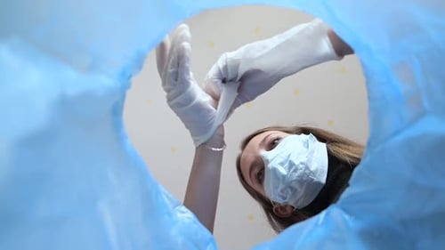 Person Disposing of Used Gloves Into a Trash Bin
