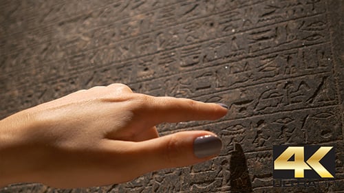 Hand Touching Ancient Stone Wall Covered in Hieroglyphs