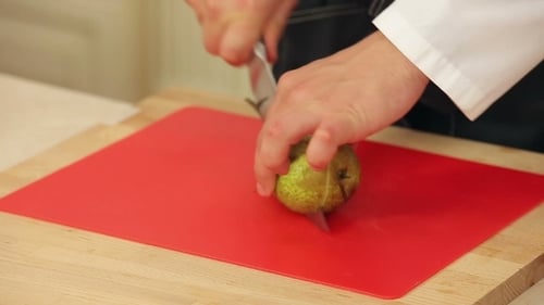 Chef Cutting And Slicing Pear On a Cutting Board