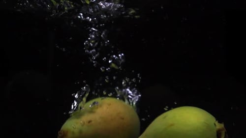 Three Pears Falls Into the Water with Splashes and Bubbles in Slow Motion.