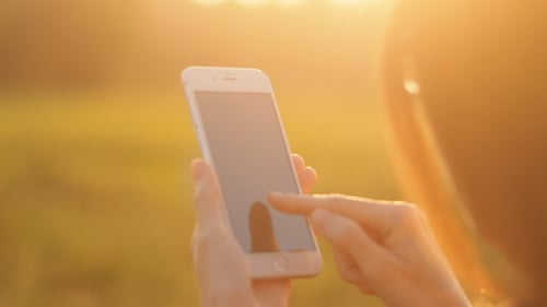 Woman Using Mobile Phone Outdoors at Sunset