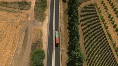 Truck loaded with Shipping Container driving on a rural highway, Aerial follow footage.