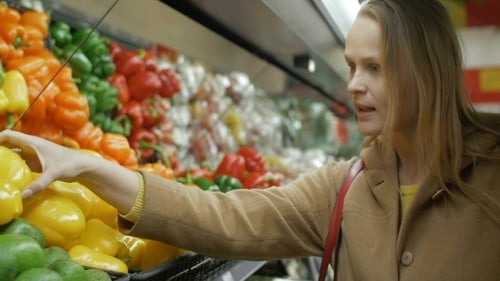 Happy Girl Buying Fresh Yellow Peppers In Grocery