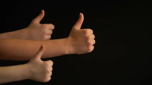 Hands Giving Thumbs Up Against a Dark Background