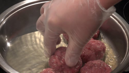 Adding Meatballs to Hot Oil in a Pan