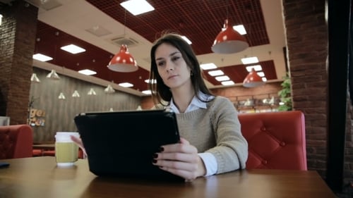 Woman Using Tablet Computer Touchscreen In Cafe