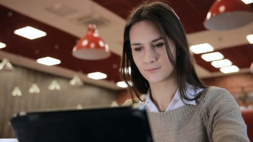 Woman Using Tablet Computer Touchscreen In Cafe