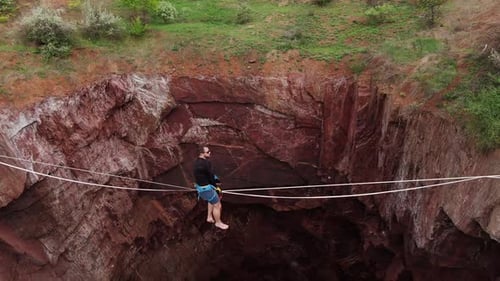 Man Slacklining Across Rocky Chasm with Safety Equipment