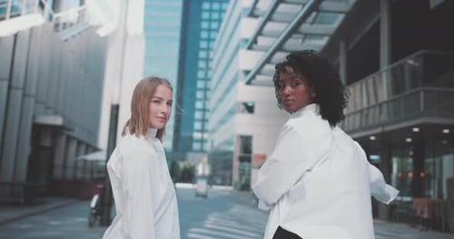 Deux jeunes femmes en tenue professionnelle, avec un vélo dans un quartier d'affaires
