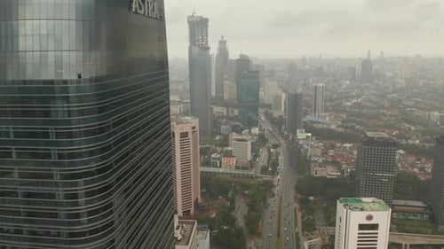 Aerial View Reveal Flying From Behind a Skyscraper To Wide View of Jakarta City Skyline Reveal