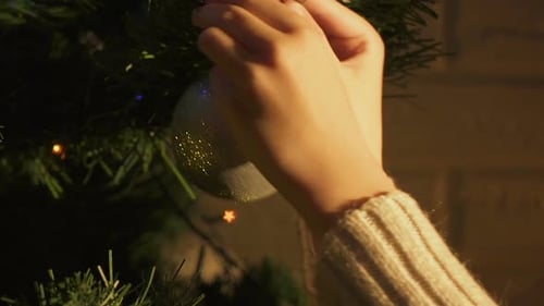Hands Decorating Christmas Tree with Silver Ornament