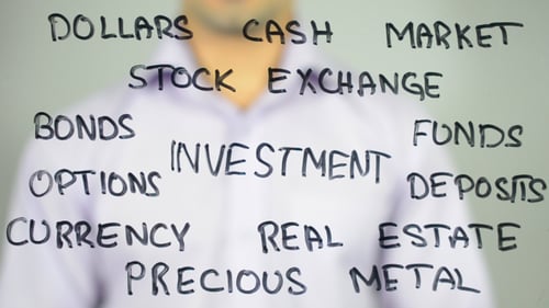 Person Writing Investment on Transparent Board