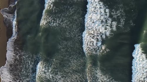 Aerial top view powerful waves on blue turquoise ocean crashing and foaming. Drone 4K footage sunny