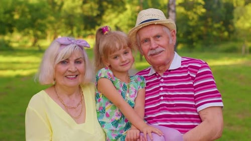 Little Granddaughter Together with Senior Grandmother and Grandfather in Park Family Relationship