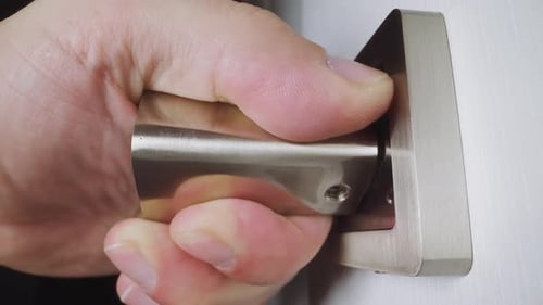 Hand Presses Down on Metal Door Handle