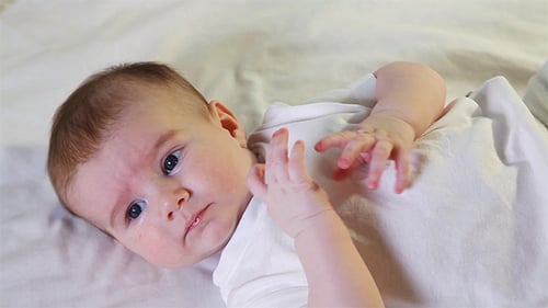 Adorable Baby Lying Down Chewing Fingers and Clothing