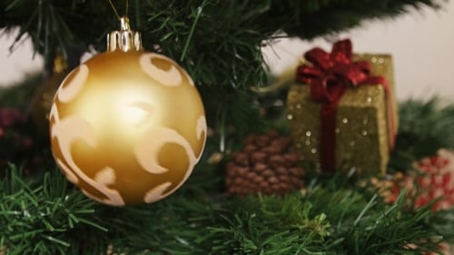 Gold Ornament Placed on Green Christmas Tree