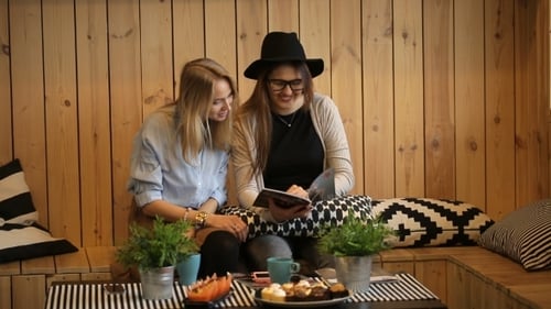 Two Women Enjoying Coffee and a Magazine Together