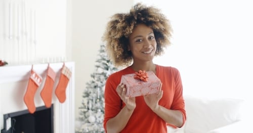 Woman Smiling Holding Christmas Gift Indoors
