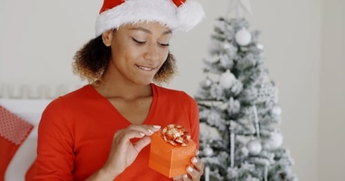 Woman Opens Christmas Gift in front of Tree