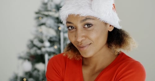 Smiling Woman in Santa Hat Near Christmas Tree