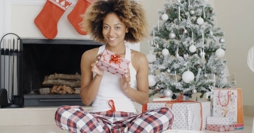 Woman Holding Christmas Gift near a Festive Tree