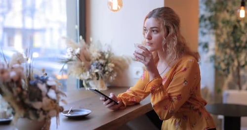 Pretty Woman Using Smart Phone Sitting in a Cafe