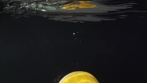 Lemon Sinking into Clear Water on Black Background