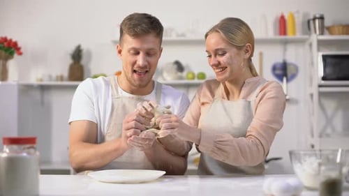 Couple Laughing while Preparing Dough in Kitchen