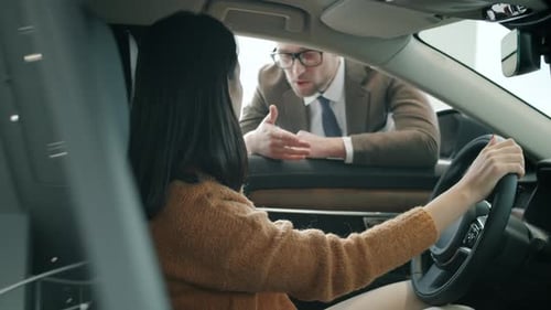 Woman in Car Talking to Salesman in Dealership