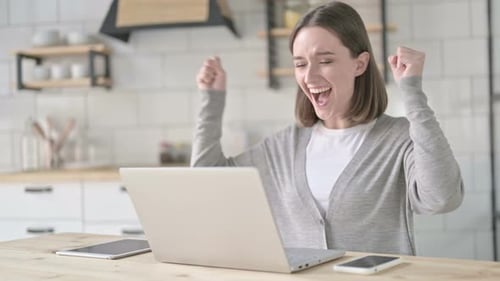 Young Woman Cheers While Working on Laptop