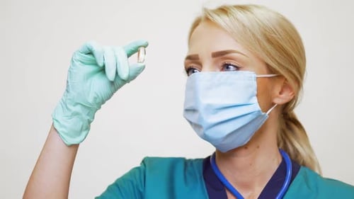 Woman in Mask Holding Pill Close Up