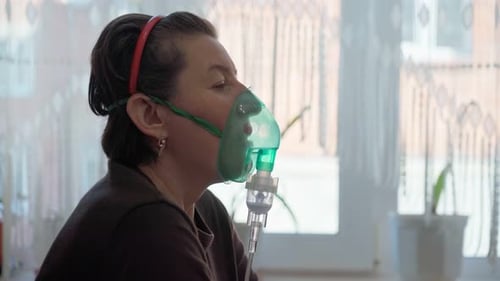 Une femme européenne à la maison effectue une inhalation de vapeurs d'huile oxygène à travers un masque