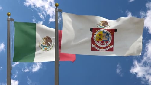 Mexico and Oaxaca Flags Waving Together on Flagpoles Against a Blue Sky