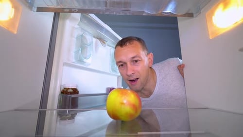 Man Takes an Apple from Empty Refrigerator