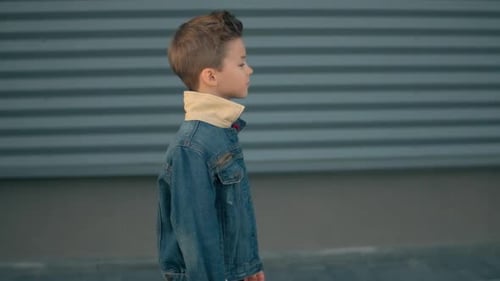 Seul, un petit garçon marche dans la rue et réfléchit. Visage d'un petit garçon triste et sérieux