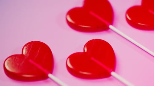 Shiny Red Heart Lollipops on Pink Background Animated Loop