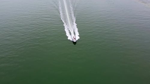 Aerial view from a drone of a white boat sailing on the blue sea Top view of a speedboat moving
