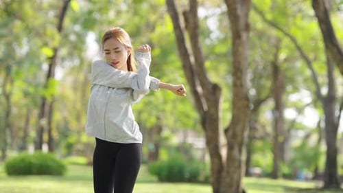 4K Asian woman stretching body while jogging exercise at public park in the morning.